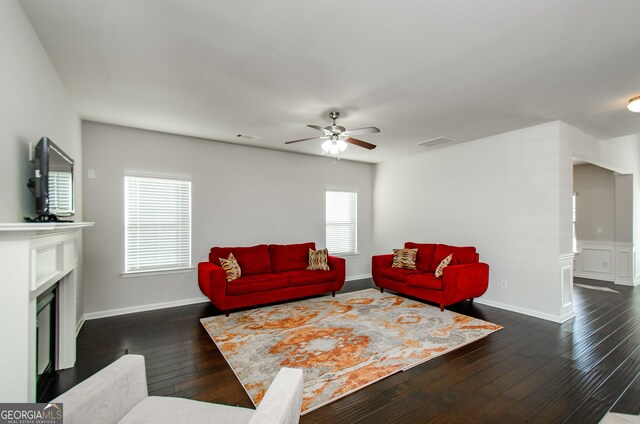 living area featuring a fireplace, visible vents, dark wood-type flooring, ceiling fan, and baseboards