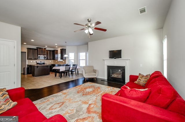 living room with recessed lighting, visible vents, light wood-style flooring, a fireplace with flush hearth, and ceiling fan