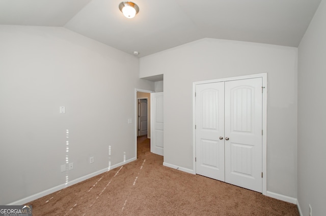 unfurnished bedroom featuring lofted ceiling, carpet floors, a closet, and baseboards