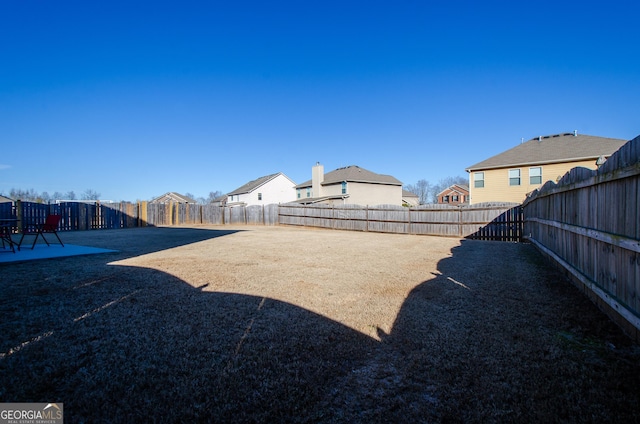 view of yard featuring a patio, a fenced backyard, and a residential view