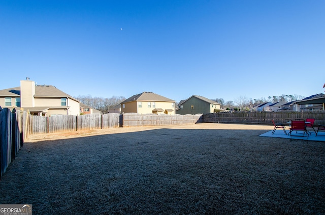 view of yard featuring a patio area, a fenced backyard, and a residential view