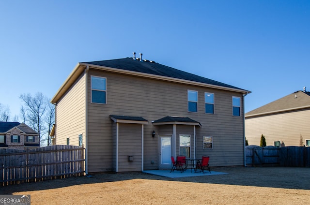 back of house with a fenced backyard and a patio