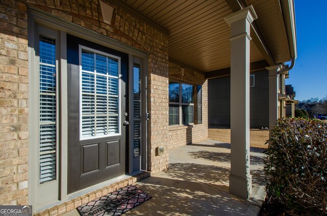 property entrance featuring a porch and brick siding