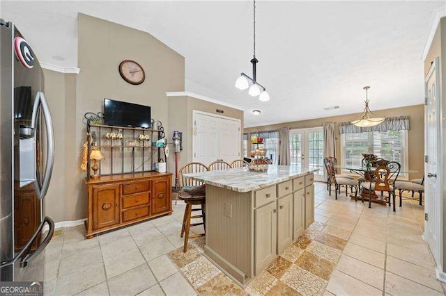 kitchen with pendant lighting, a breakfast bar, a center island, light stone counters, and stainless steel fridge with ice dispenser