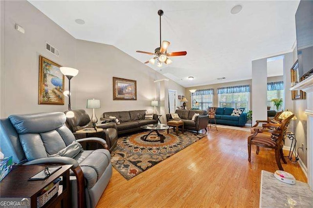 living room with a fireplace, hardwood / wood-style floors, vaulted ceiling, and ceiling fan