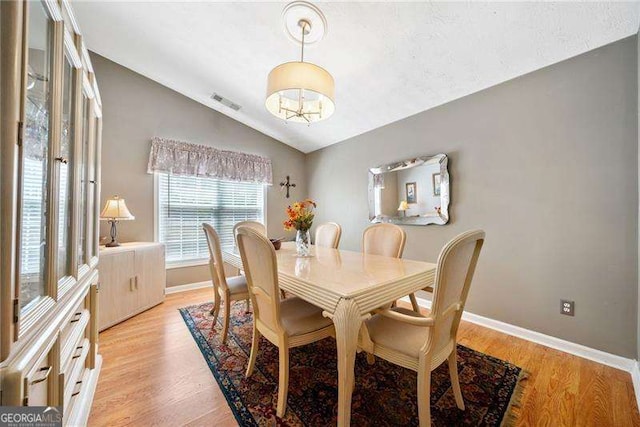 dining room featuring vaulted ceiling and light wood-type flooring