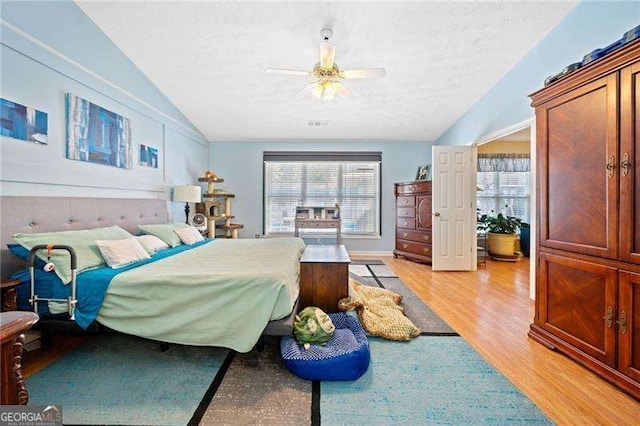 bedroom with a textured ceiling, ceiling fan, lofted ceiling, and light wood-type flooring