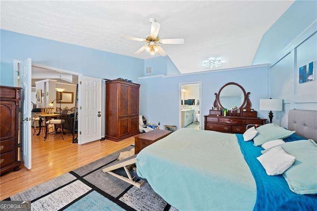 bedroom featuring ensuite bathroom, vaulted ceiling, hardwood / wood-style flooring, ceiling fan, and a textured ceiling