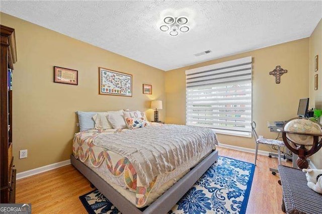 bedroom featuring light hardwood / wood-style floors and a textured ceiling