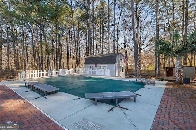 view of pool with a patio area, a diving board, and a storage shed