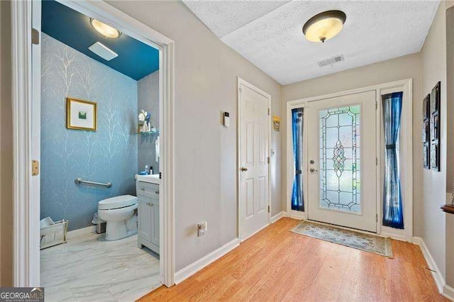 foyer featuring a textured ceiling and light hardwood / wood-style flooring