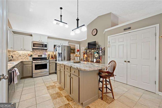 kitchen with lofted ceiling, decorative light fixtures, decorative backsplash, a kitchen island, and appliances with stainless steel finishes