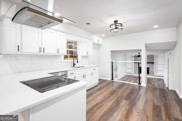 kitchen featuring sink, white cabinetry, island range hood, a textured ceiling, and backsplash