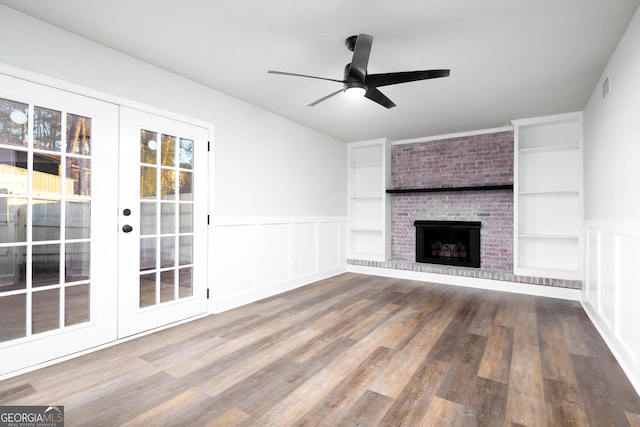 unfurnished living room featuring wood-type flooring, a fireplace, built in features, and ceiling fan