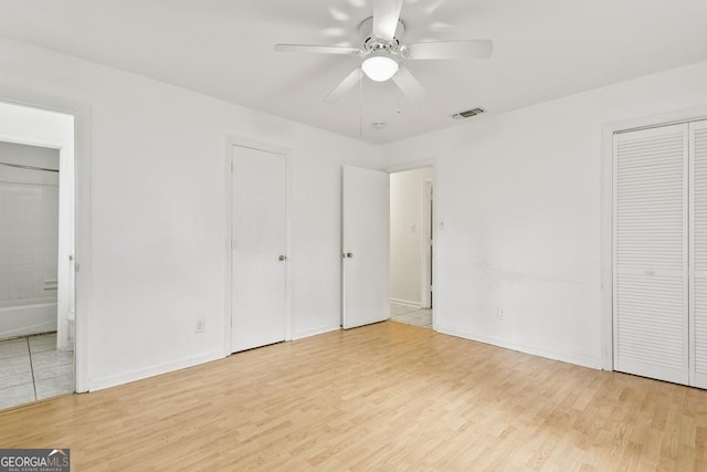 unfurnished bedroom with connected bathroom, ceiling fan, and light hardwood / wood-style flooring