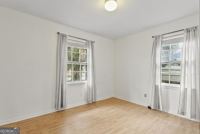 empty room with plenty of natural light and light hardwood / wood-style flooring