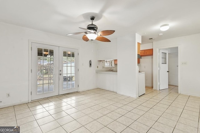 unfurnished living room with french doors, sink, ceiling fan, light tile patterned floors, and washer / clothes dryer