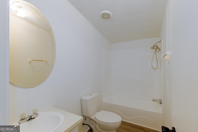 full bathroom featuring sink, hardwood / wood-style floors, a textured ceiling, and toilet