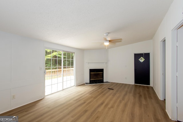 unfurnished living room featuring hardwood / wood-style floors, ceiling fan, and a textured ceiling