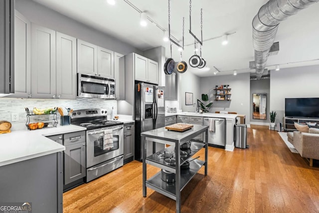 kitchen featuring gray cabinetry, decorative backsplash, stainless steel appliances, and light wood-type flooring