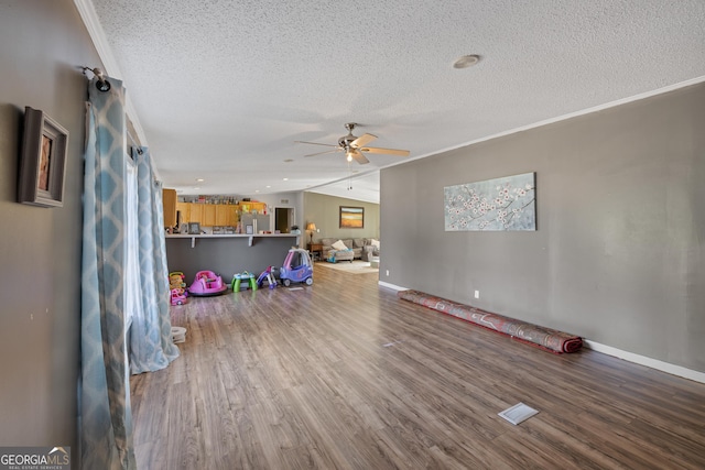 interior space featuring ceiling fan, hardwood / wood-style floors, a textured ceiling, vaulted ceiling, and ornamental molding