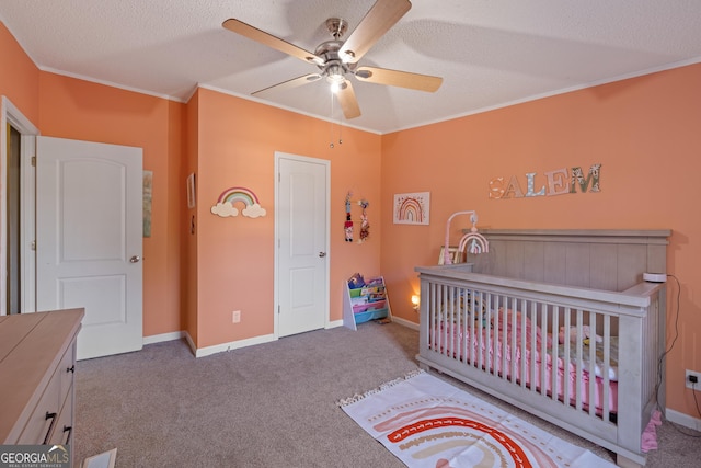 carpeted bedroom featuring a textured ceiling, ceiling fan, crown molding, and a nursery area