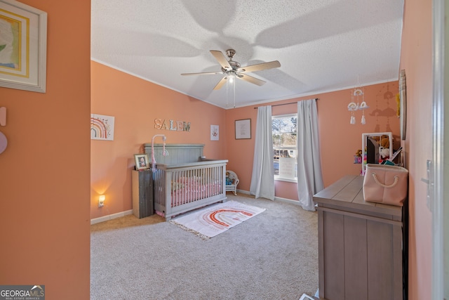 carpeted bedroom with a crib, a textured ceiling, and ceiling fan