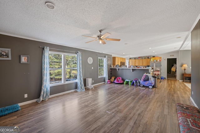 exercise area featuring ceiling fan, crown molding, hardwood / wood-style floors, vaulted ceiling, and a textured ceiling