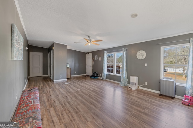 unfurnished living room with radiator heating unit, hardwood / wood-style flooring, ceiling fan, and crown molding