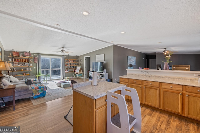 kitchen featuring a center island, lofted ceiling, light hardwood / wood-style flooring, ceiling fan, and a textured ceiling