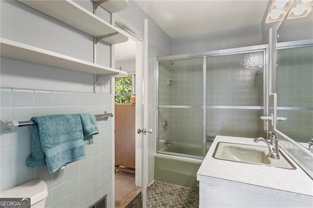 bathroom with tile walls, vanity, and combined bath / shower with glass door