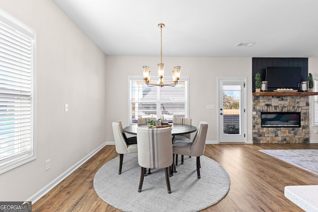 dining space featuring wood-type flooring, a fireplace, and an inviting chandelier