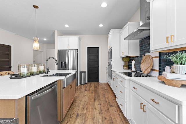 kitchen featuring stainless steel appliances, white cabinetry, and wall chimney range hood