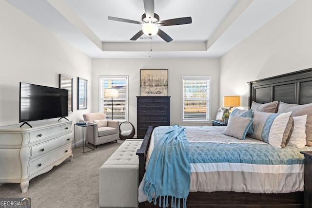 carpeted bedroom featuring ceiling fan and a raised ceiling