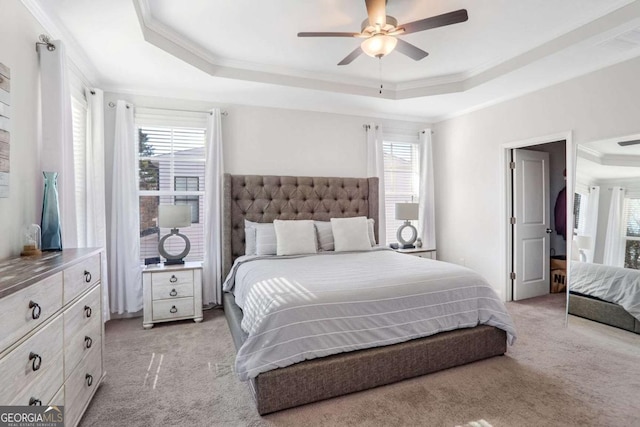 carpeted bedroom with multiple windows, a raised ceiling, and ceiling fan