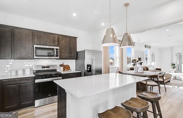 kitchen featuring appliances with stainless steel finishes, a center island, pendant lighting, and backsplash