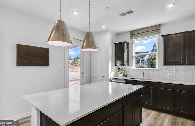 kitchen with sink, a center island, tasteful backsplash, light hardwood / wood-style flooring, and pendant lighting