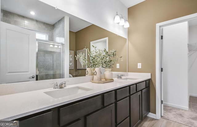 bathroom with hardwood / wood-style floors, vanity, and a shower with door