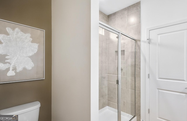 bathroom with a shower with door and toilet