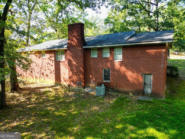 rear view of property with a yard and central AC unit