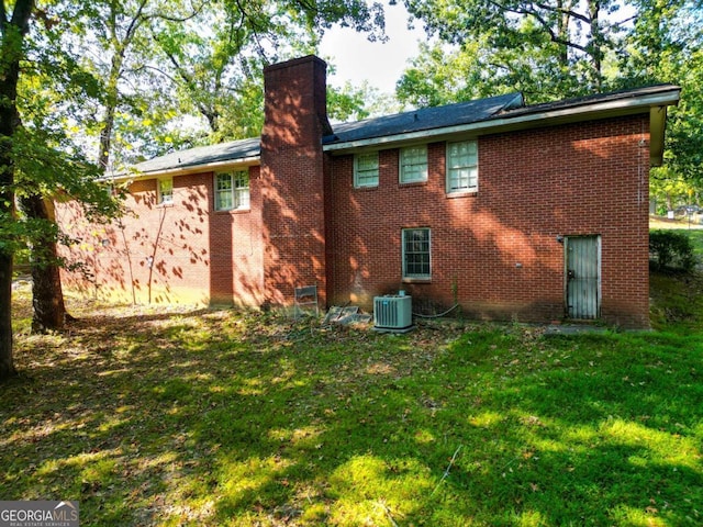 rear view of house with a yard and central AC