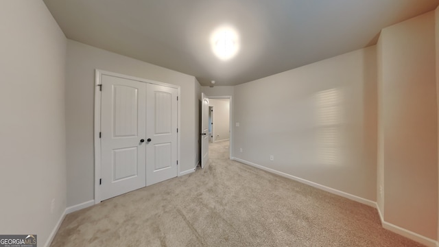 unfurnished bedroom featuring light colored carpet and a closet