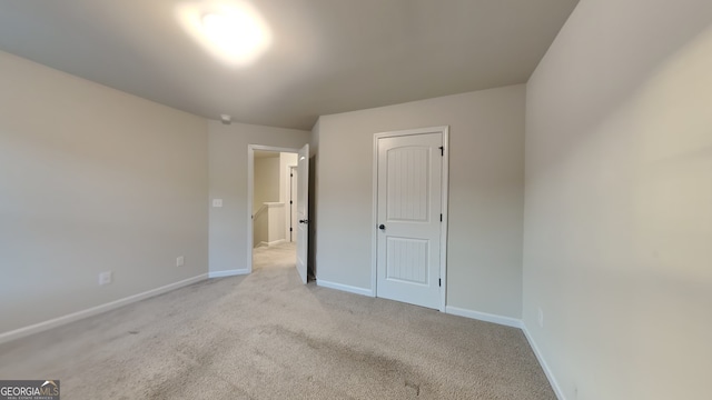 unfurnished bedroom with light colored carpet and a closet