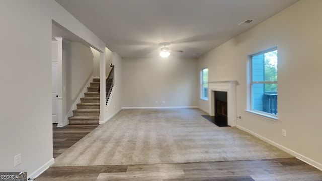 unfurnished living room with dark hardwood / wood-style flooring and ceiling fan