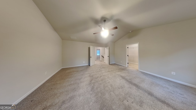 spare room featuring ceiling fan, light carpet, and vaulted ceiling