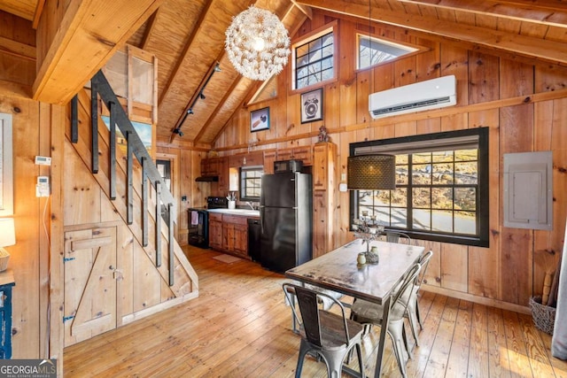 dining space with light hardwood / wood-style flooring, an inviting chandelier, vaulted ceiling with beams, and a wall unit AC