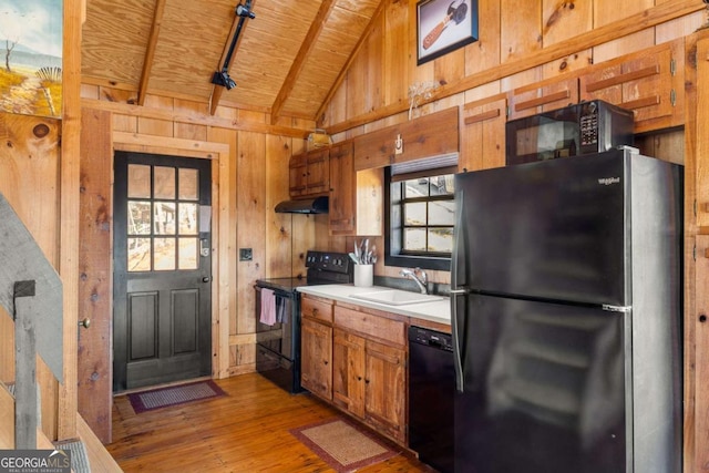 kitchen with black appliances, wood ceiling, wood walls, and sink