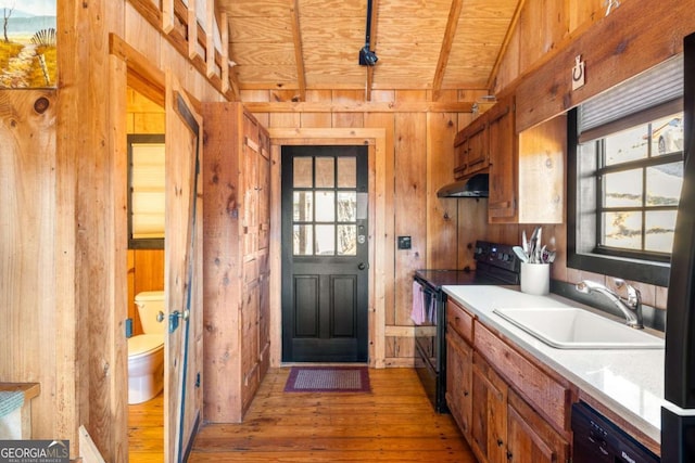 kitchen featuring sink, wooden ceiling, vaulted ceiling, wooden walls, and black appliances