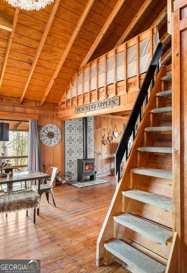 interior space with hardwood / wood-style floors, vaulted ceiling with beams, a wood stove, and wood walls