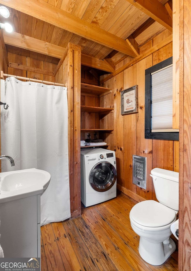 bathroom featuring heating unit, wood walls, washer / dryer, beam ceiling, and sink